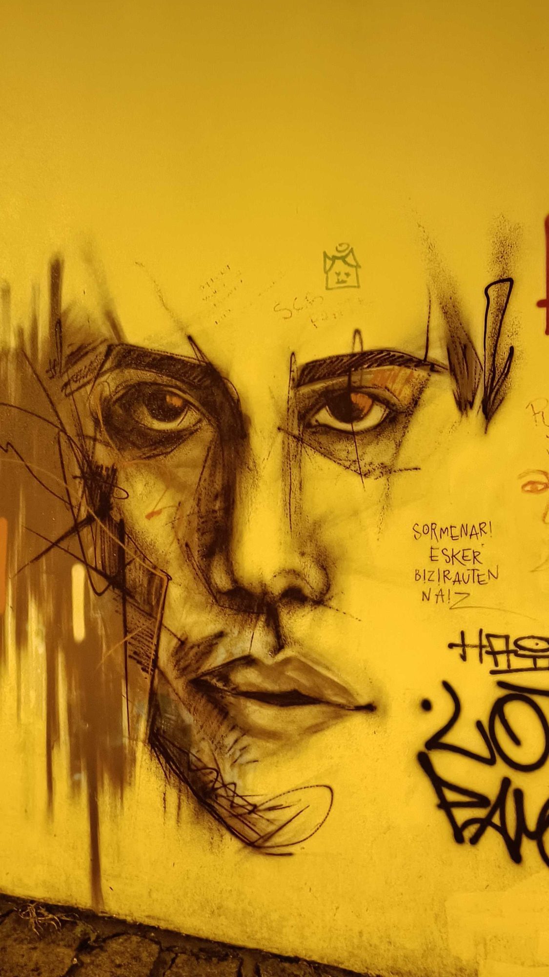 Visage expressif sur mur jaune — Street art à Porto