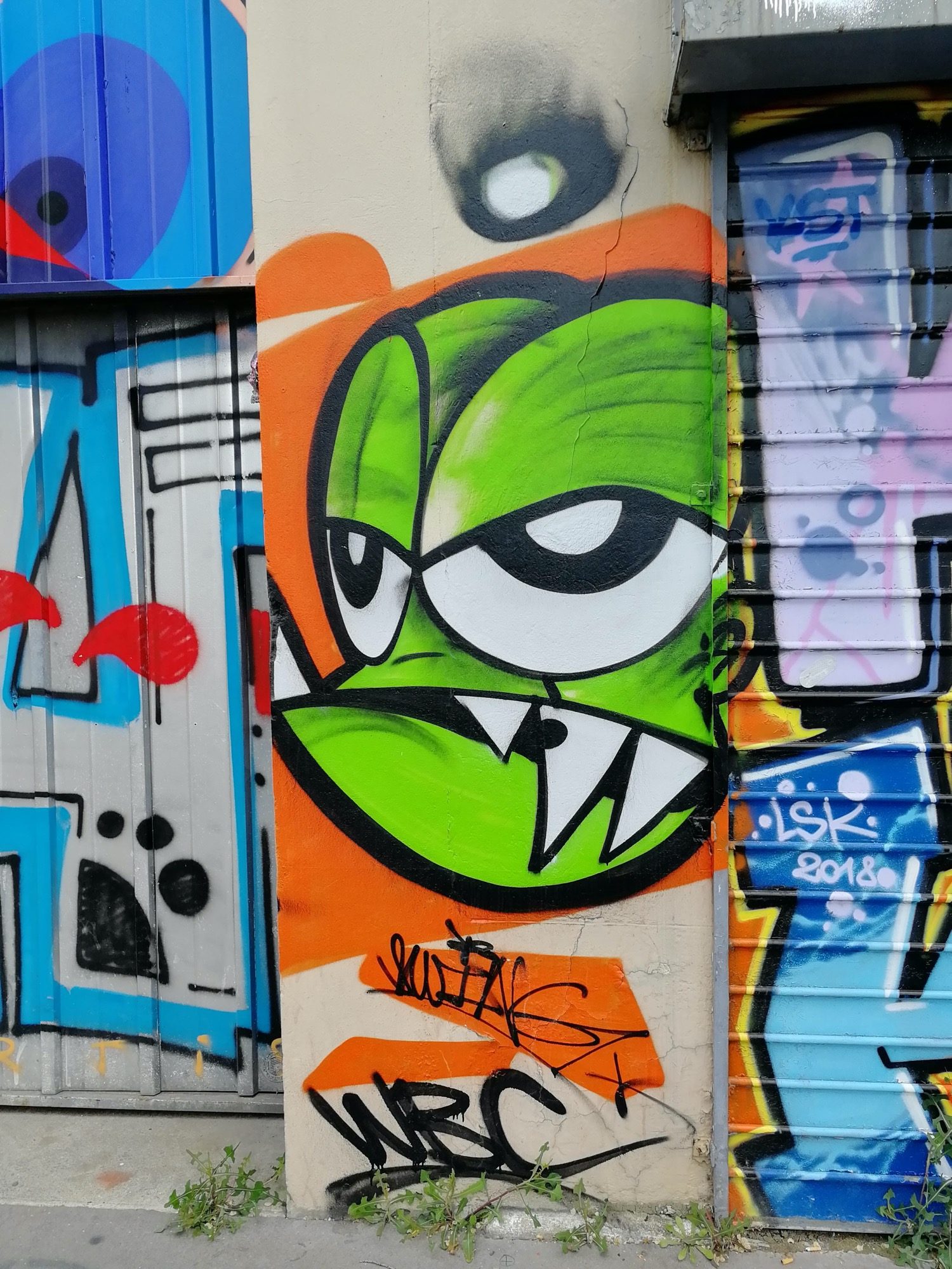 Monstre vert aux crocs sur fond orange — Street art à Lyon