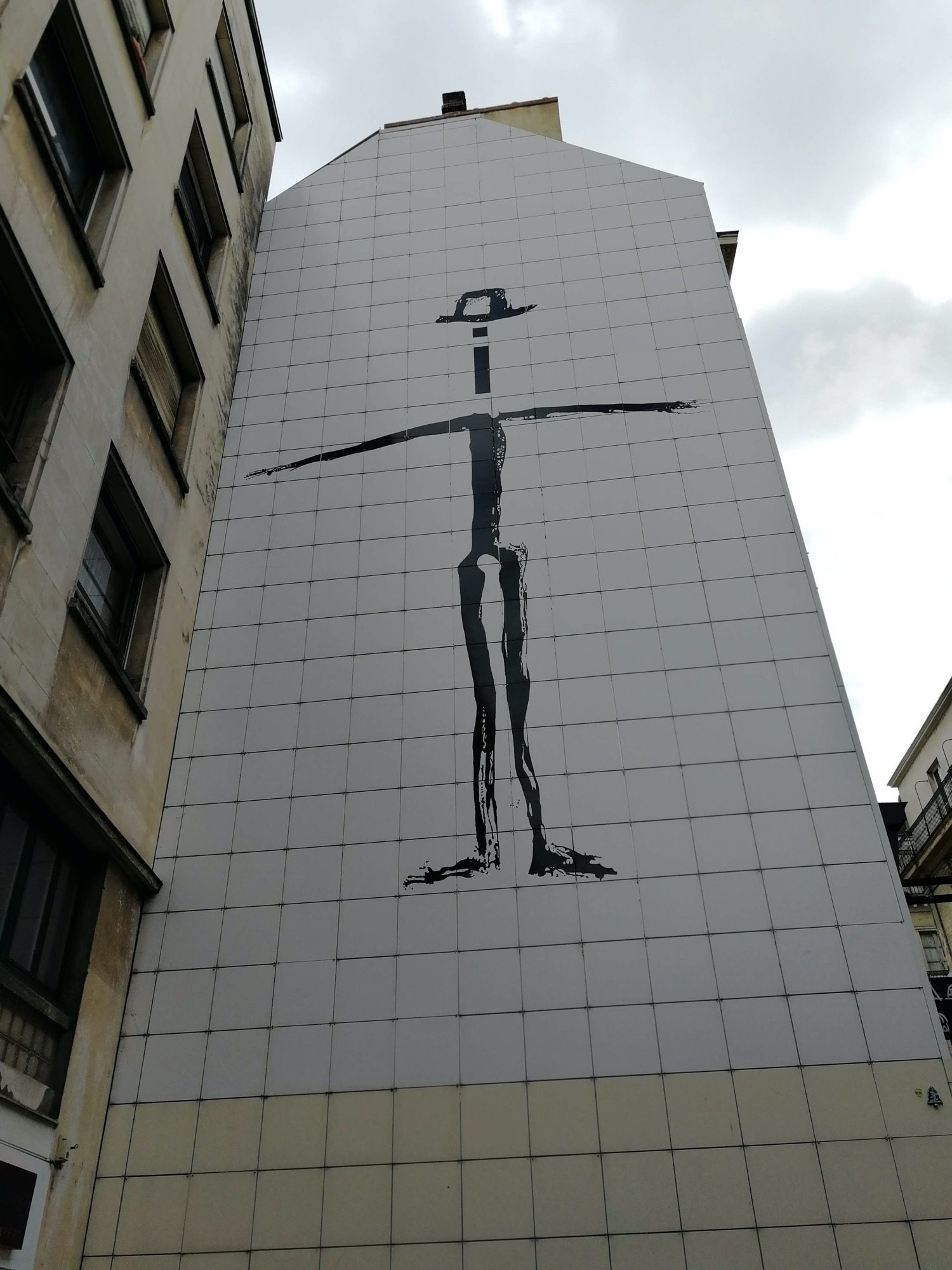 Cross-Arm Silhouette on White Facade — Street art in Nantes