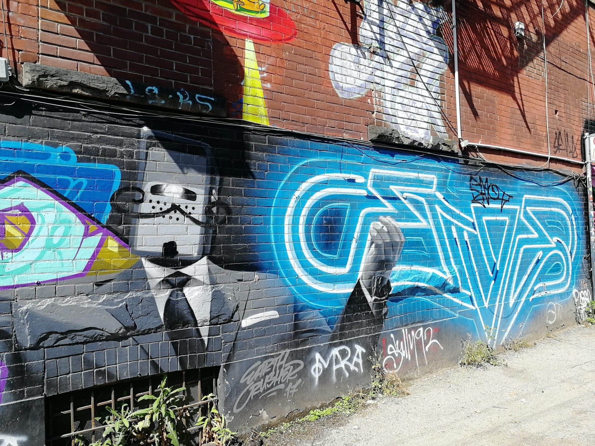 Suited masked figure and blue lettering — Street art in Toronto