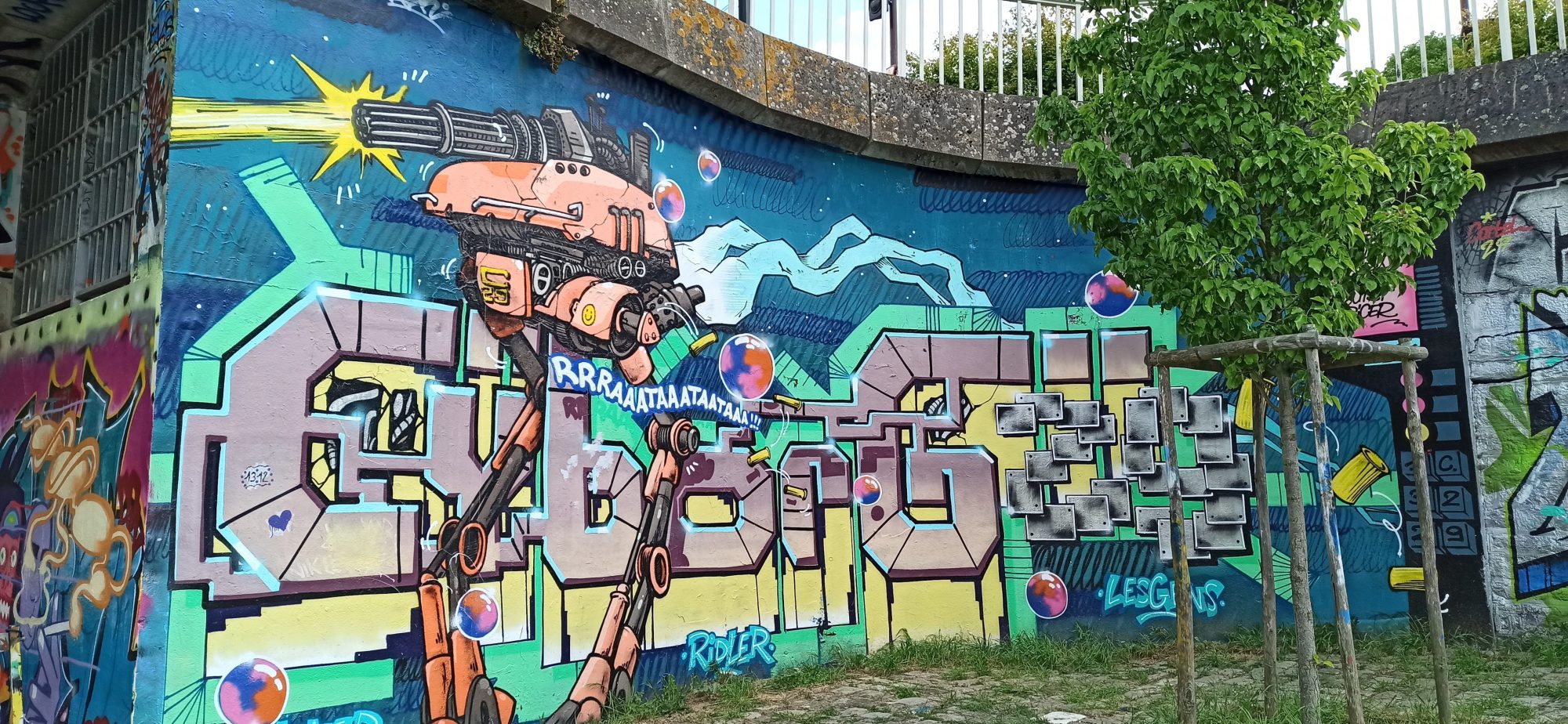 Robot armé et graffiti coloré — Street art à Nantes