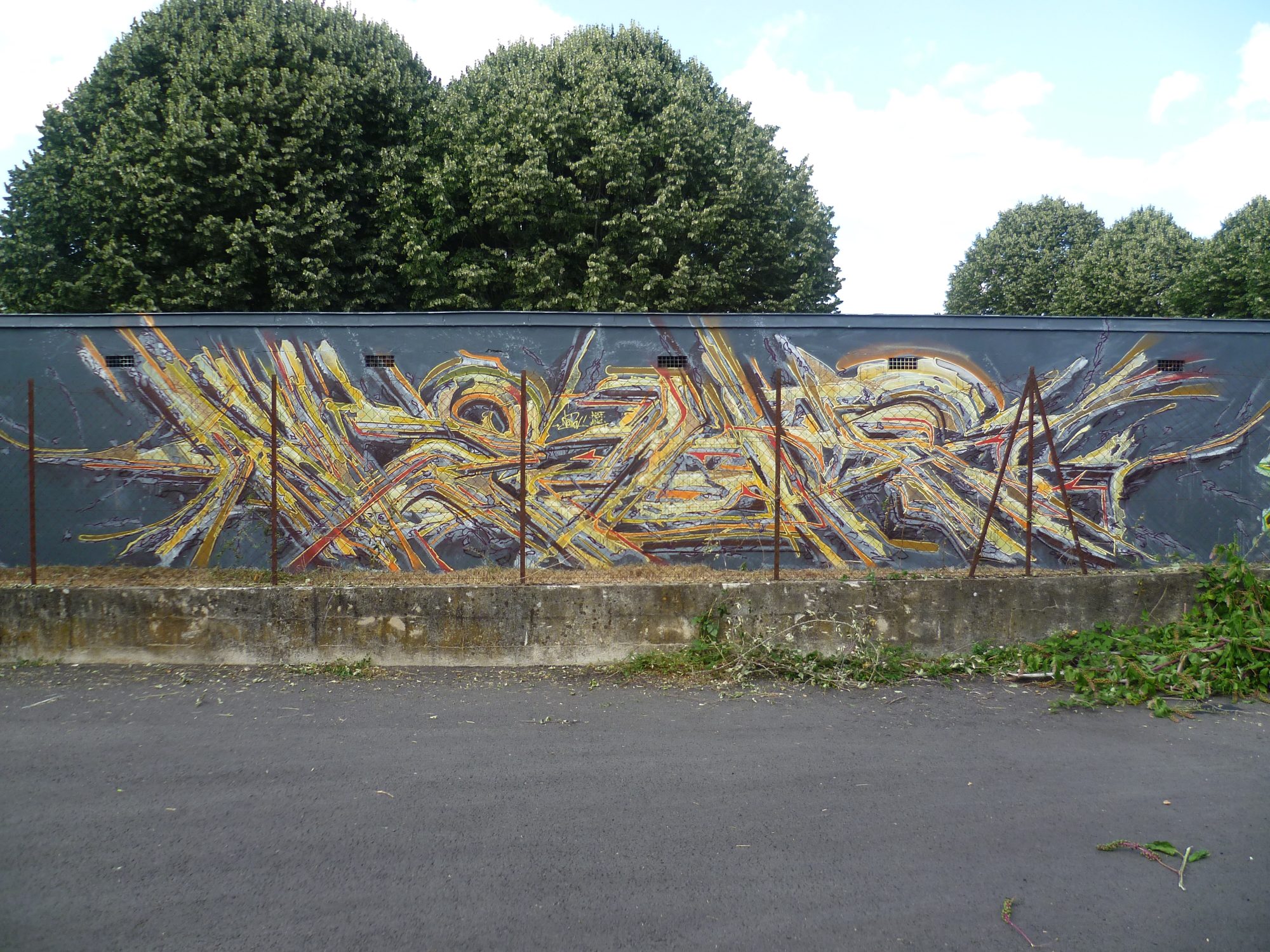 Shattered yellow lettering on a dark wall — Street art in Coulounieix-Chamiers