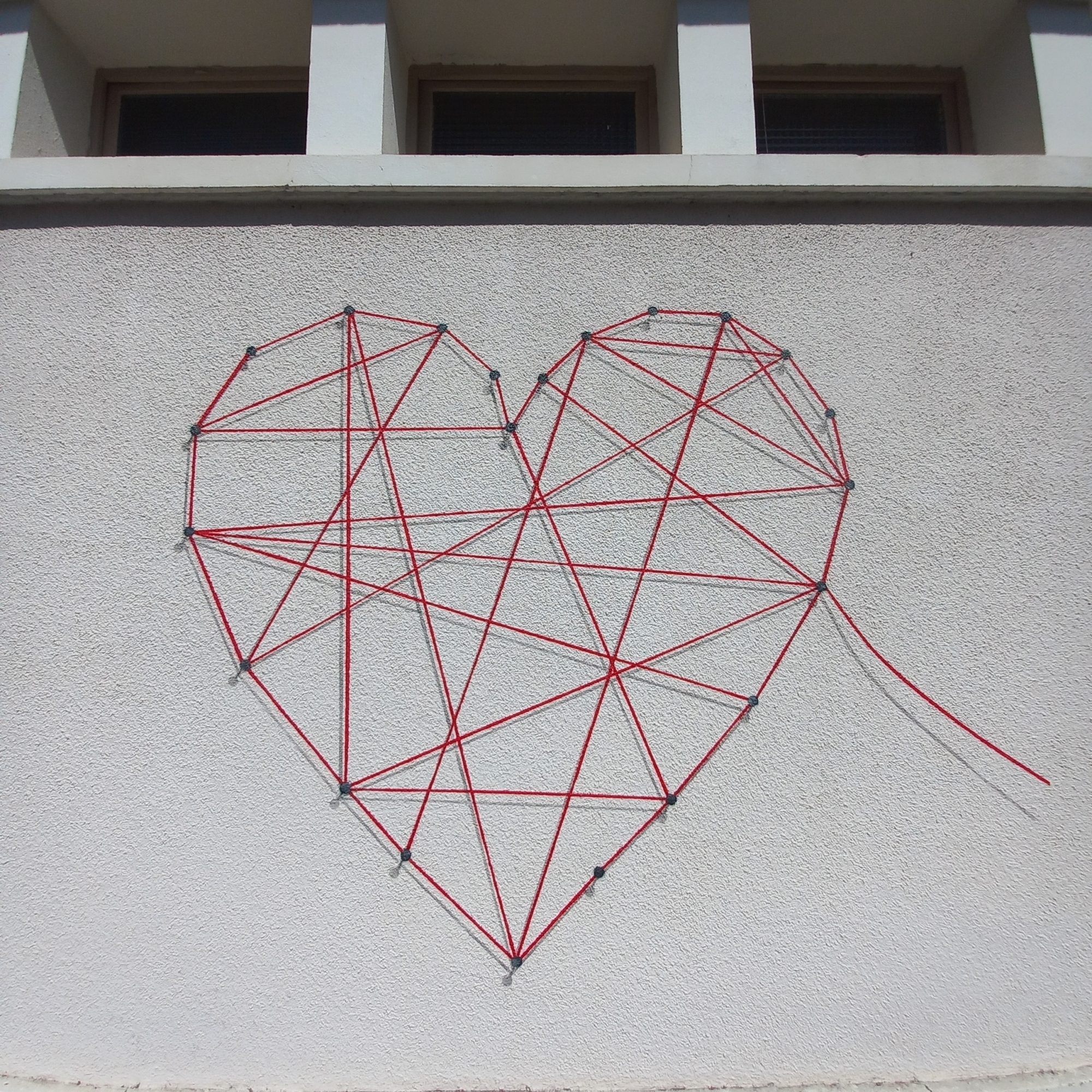Cœur géométrique en fils rouges — Street art à Cransac-les-Thermes