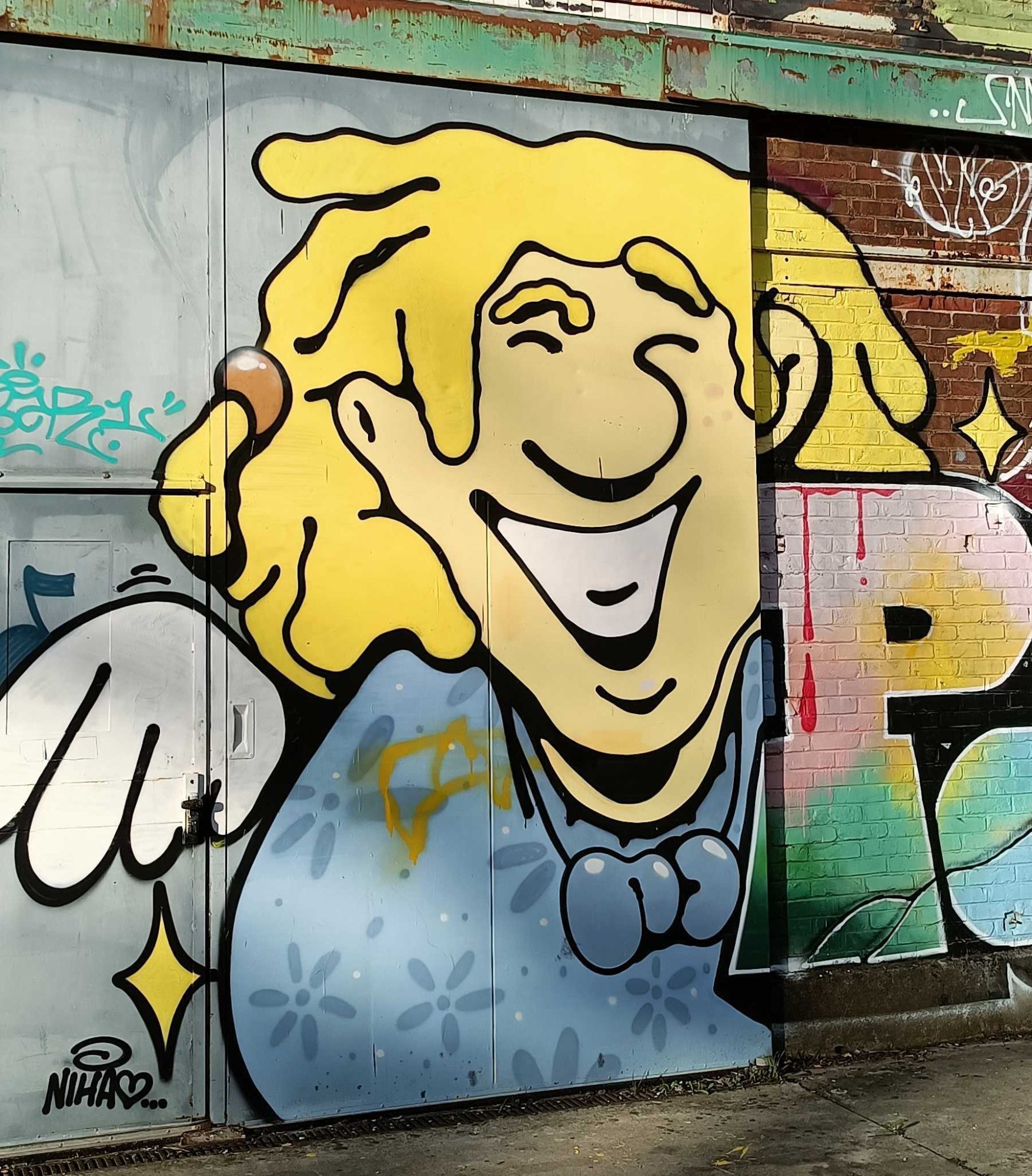 Fillette blonde hilare signée NIHA — Street art à Rennes