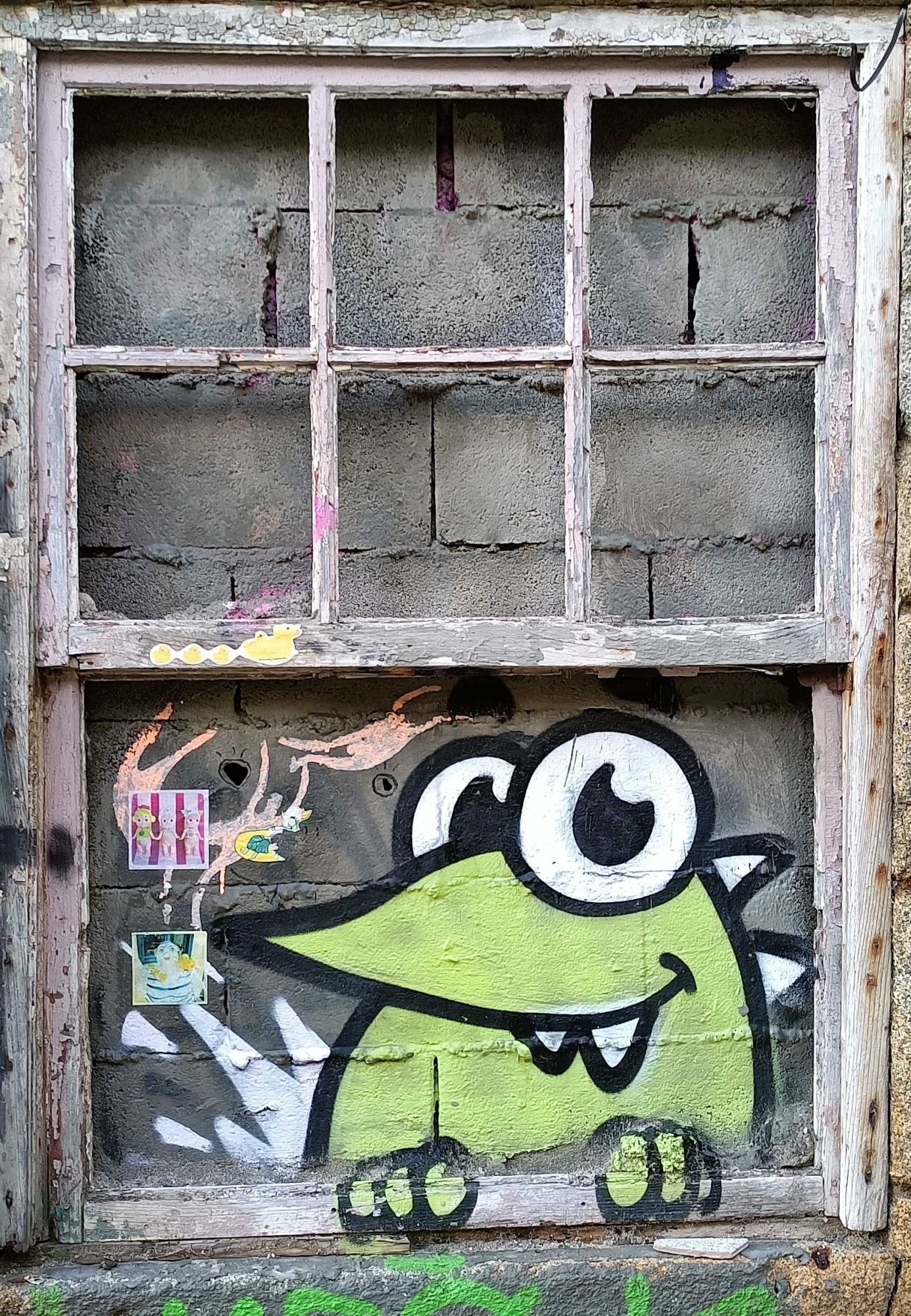 Monstre vert sous la fenêtre brisée — Street art à Porto