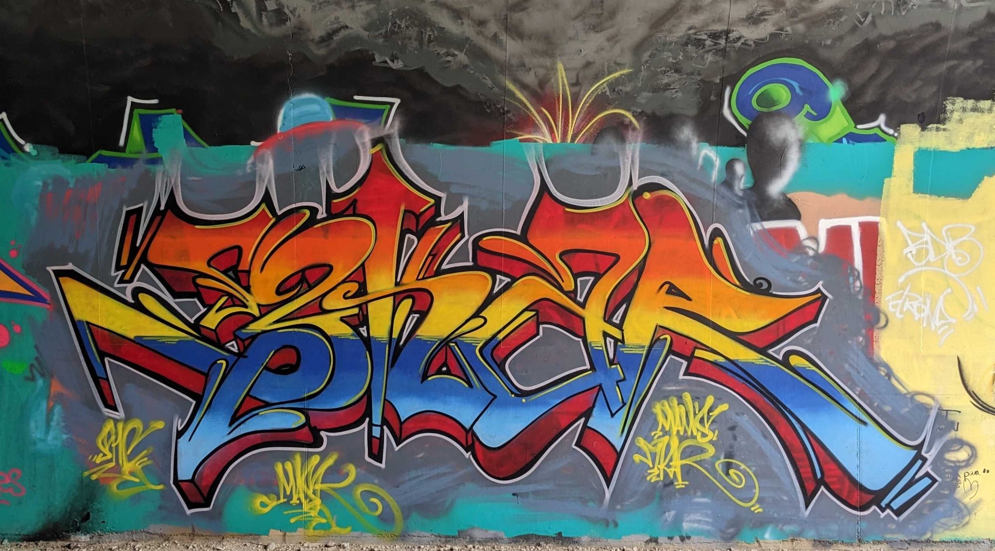 Lettrage orange et bleu au personnage casqué — Street art à Soyons