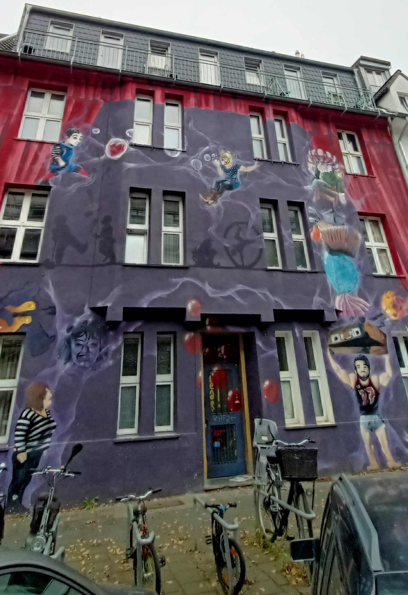 Façade violette aux figures flottantes — Street art à Düsseldorf