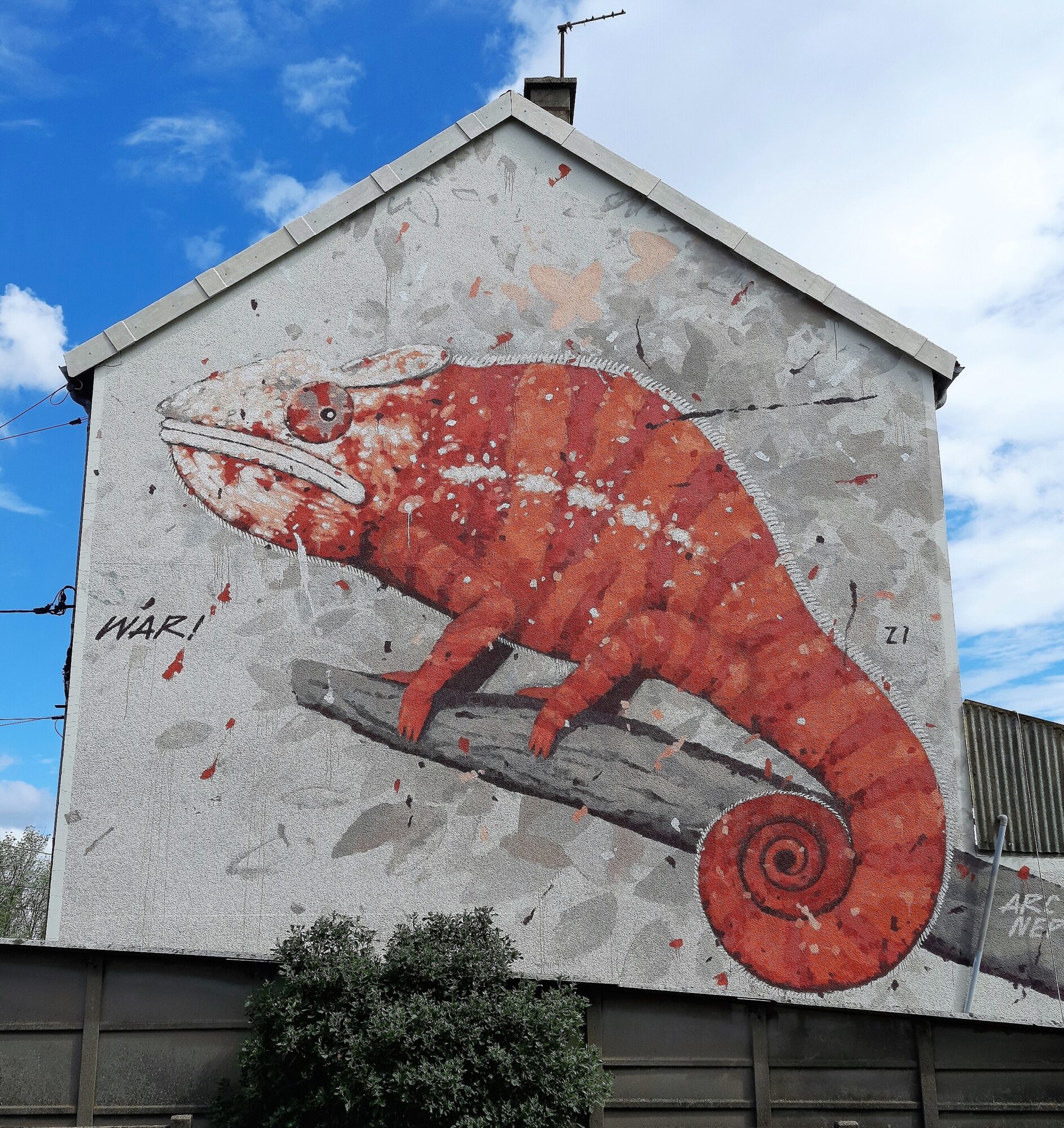 Red chameleon on a gable wall — Street art by War in Le Mans
