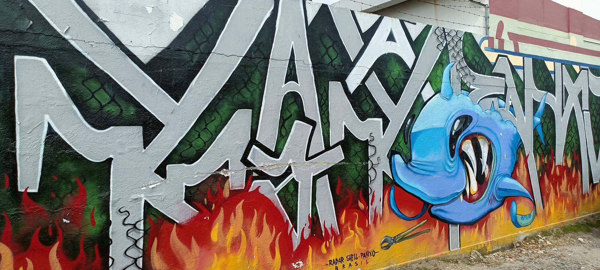 Silver Lettering over Flames with Blue Creature — Street art in Almada