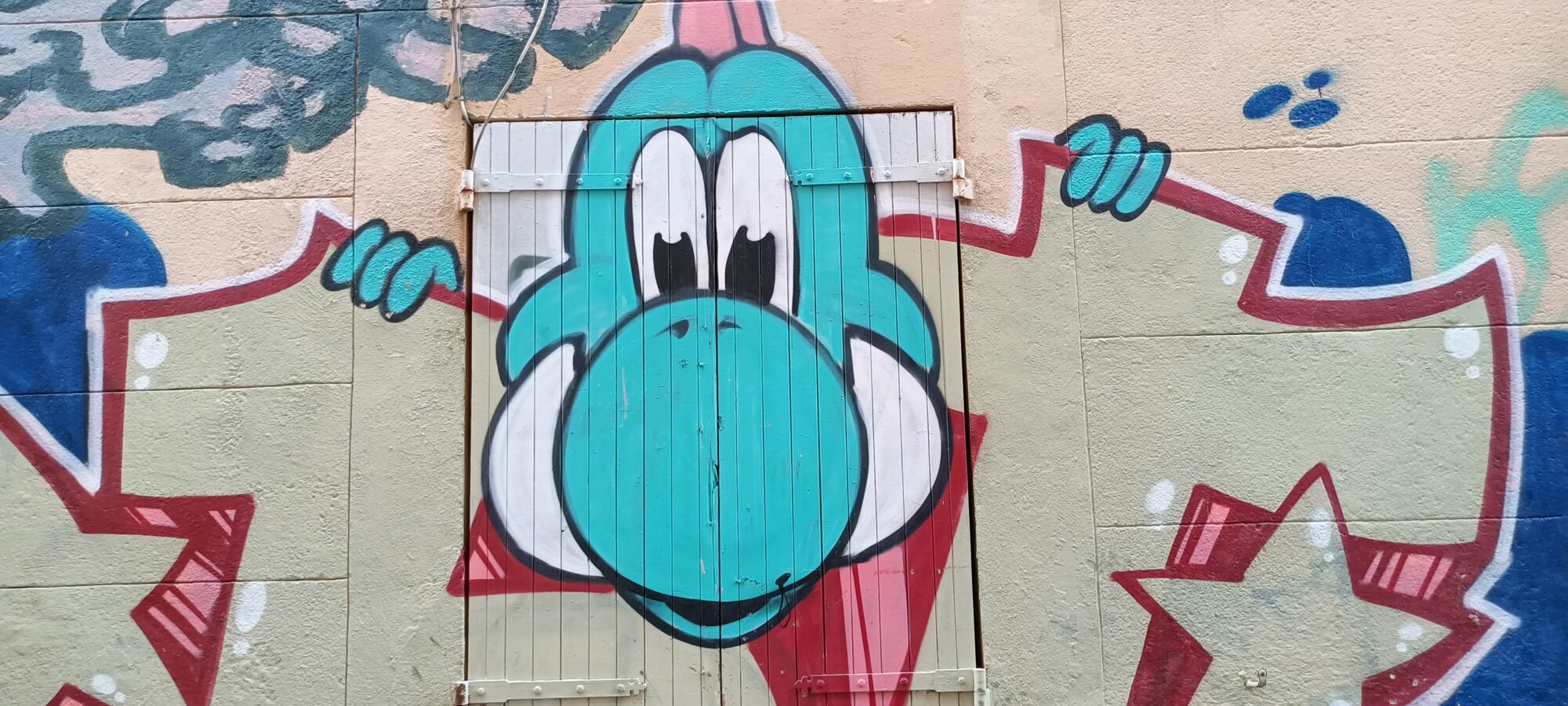 Turquoise Yoshi on a wooden door — Street art in Marseille