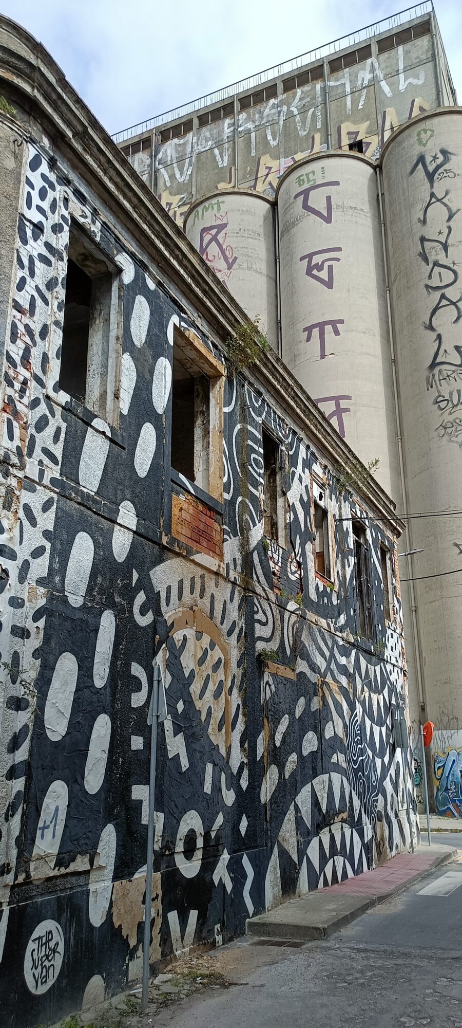 Façade à motifs noirs et blancs et silos — Street art de The Super Van à Almada