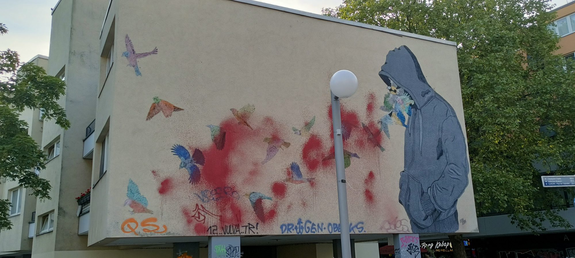 Hooded Figure with Birds at Mehringplatz — Street art in Berlin