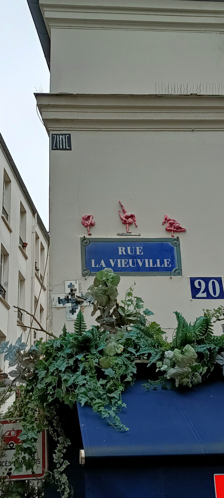 Trois acrobates roses au-dessus de la plaque — Street art à Paris