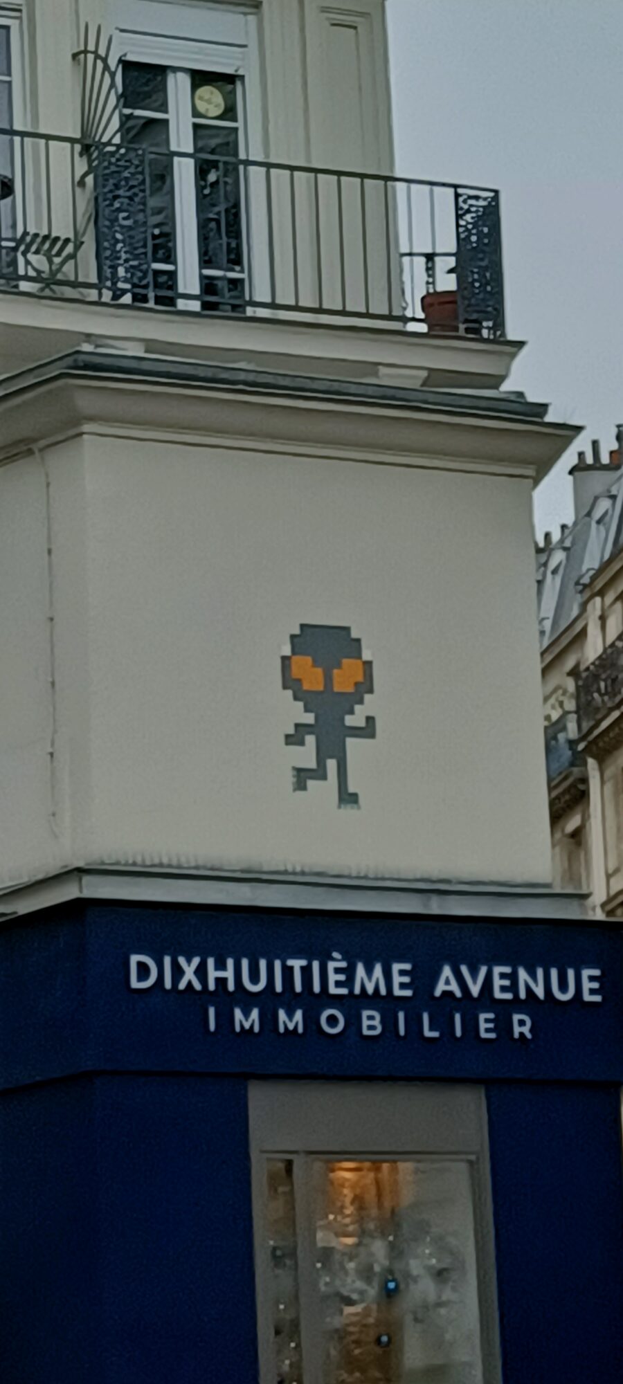 Alien pixelisé aux yeux orange — Street art de Mr Djoul à Paris