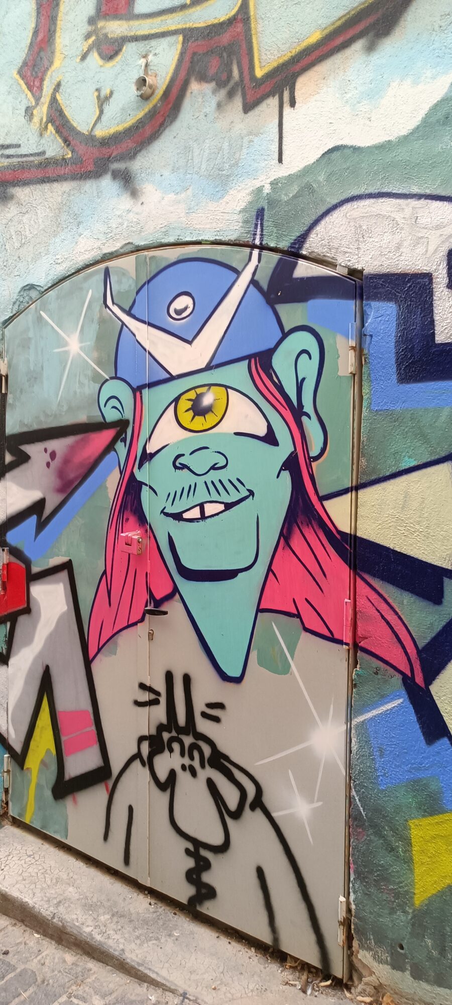 Cyclope aux cheveux roses sur porte de fer — Street art à Marseille