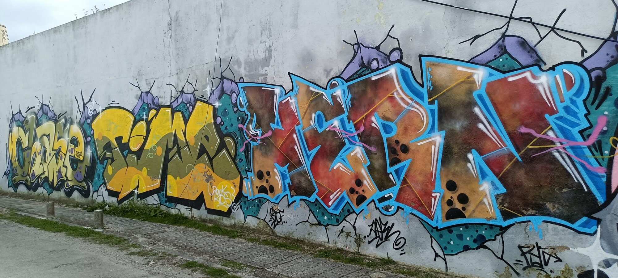 Enfilade de lettrages bleu et rouille — Street art à Almada