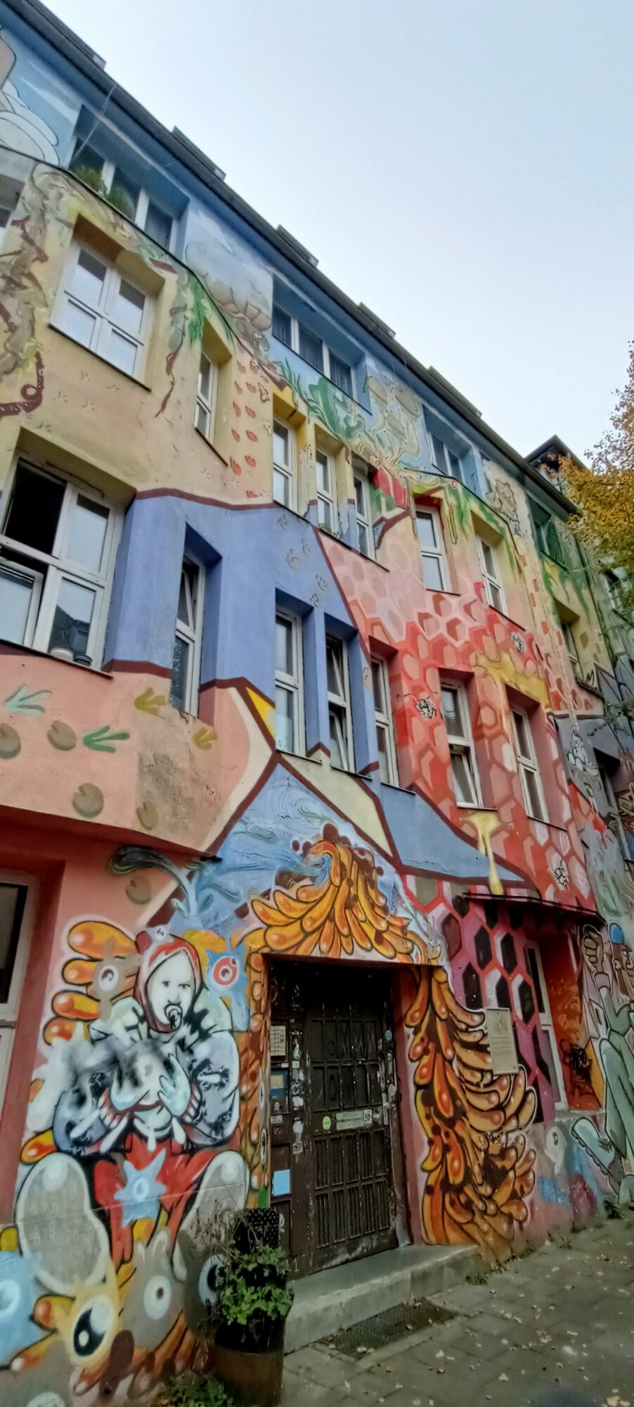 Schöner Wohnen, the faces above the doorway — Street art by Klaus Klinger in Düsseldorf
