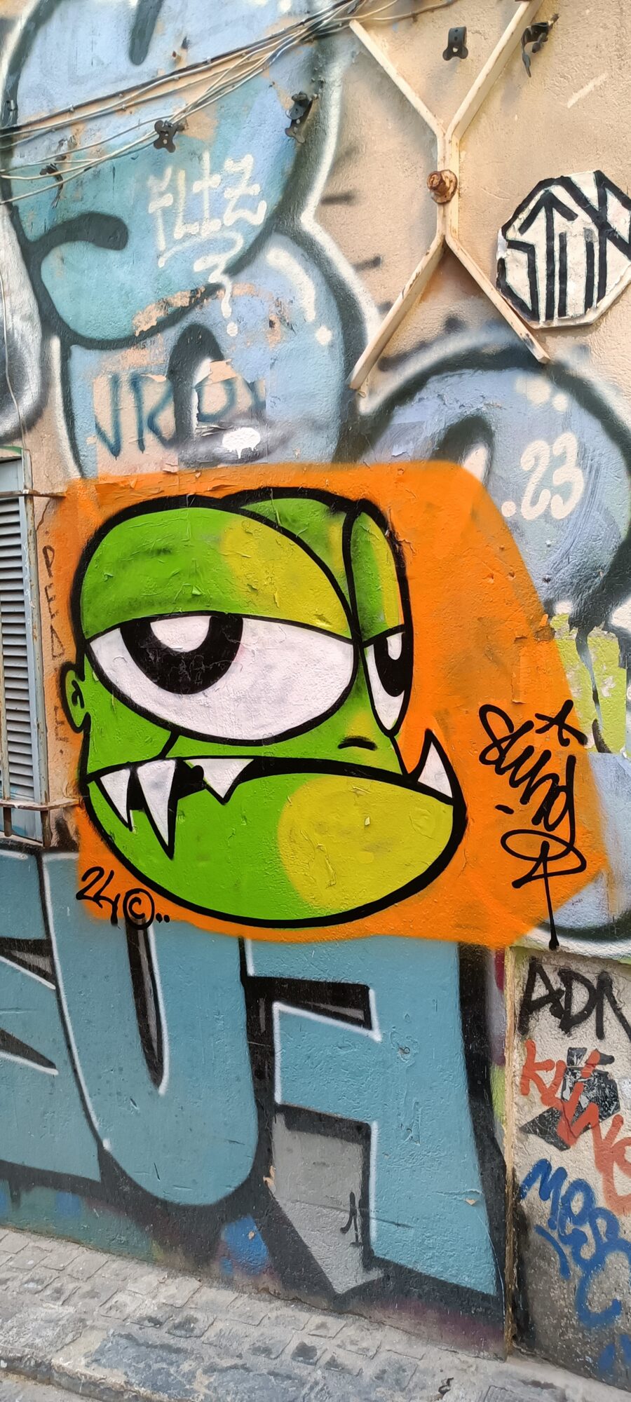Monstre cyclope vert sur fond orange — Street art à Marseille