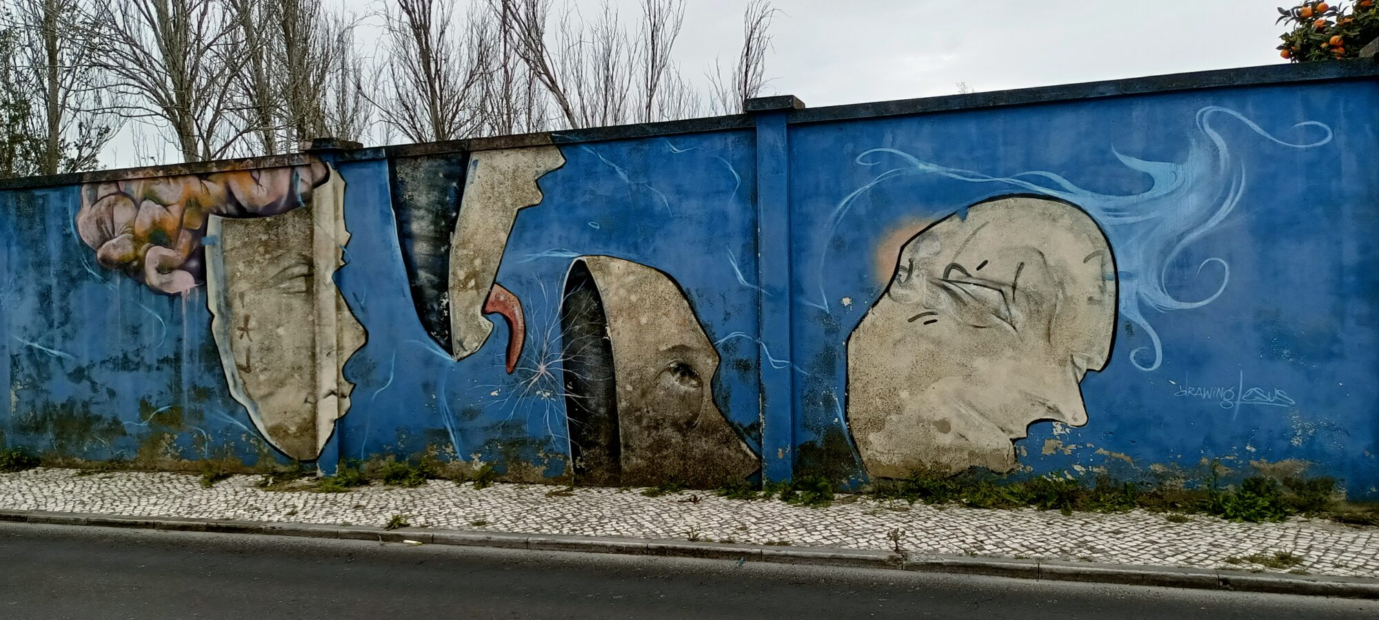 Faces under torn concrete — Street art in Lisboa