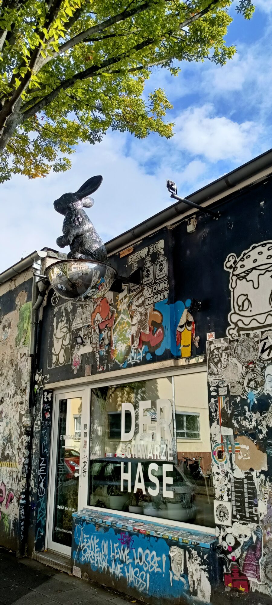 Sticker-covered facade of Der Schwarze Hase — Street art in Köln
