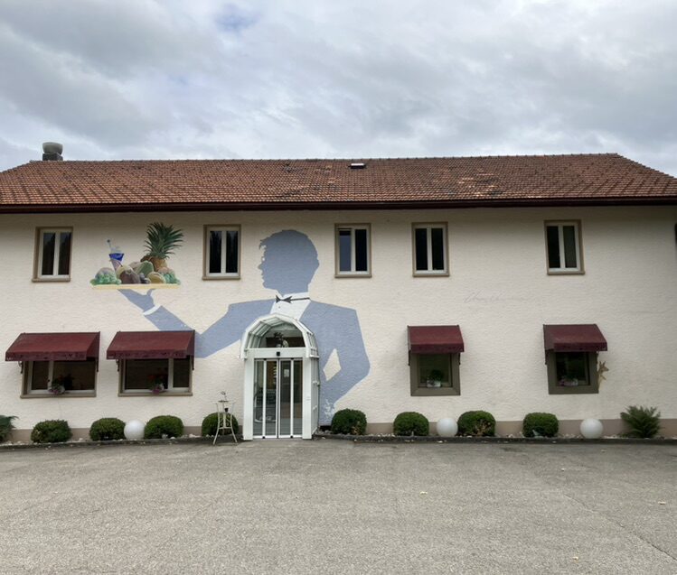 The Waiter with a Tray at Le Chevreuil — Street art by Carolus in La Chaux-de-Fonds
