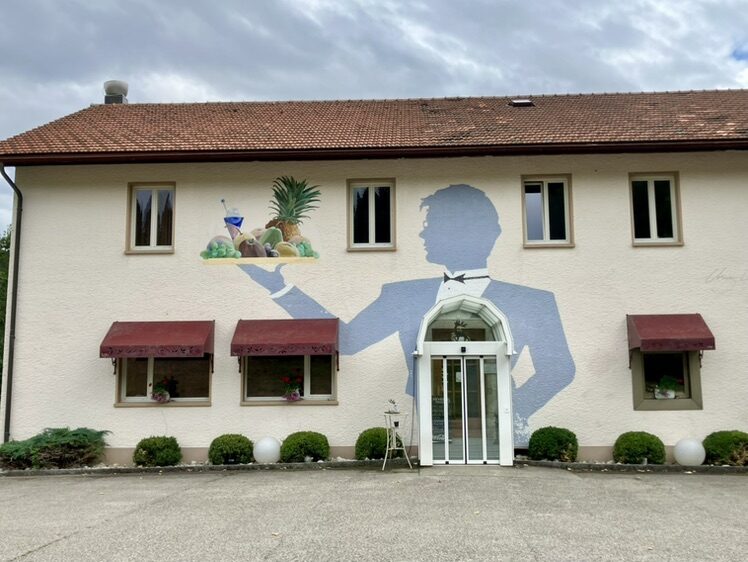 The Waiter with a Tray at Le Chevreuil — Street art by Carolus in La Chaux-de-Fonds