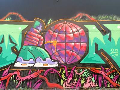 Fist Gripping a Neon Fluorescent Globe — Street art in Rīga
