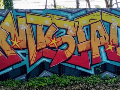 Lettrage orange aux étoiles — Street art à Nantes