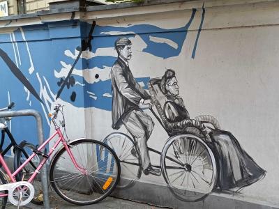 Homme poussant une femme en fauteuil retro — Street art à Rīga