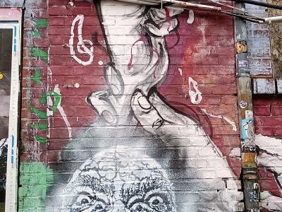Main et visage hurlant sur mur de brique — Street art à Berlin