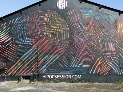 Swirling Rainbow Lines on Black Facade — Street art in Nantes