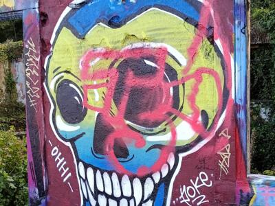 Crâne bleu et jaune recouvert d'un tag rose — Street art à Lisboa