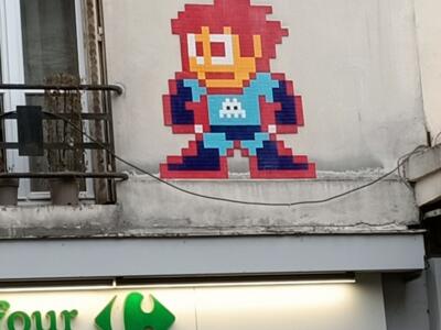Pixelated Mega Man with a small alien — Street art by Invader in Paris
