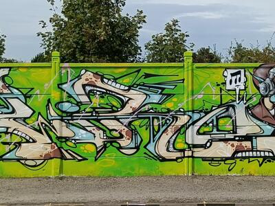 Lettrage crème et personnage au casque audio — Street art à Reims