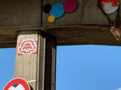 CMYK dots and a Pac-Man ghost under the bridge — Street art by Invader in Köln