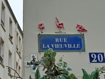 Trois acrobates roses au-dessus de la plaque — Street art à Paris