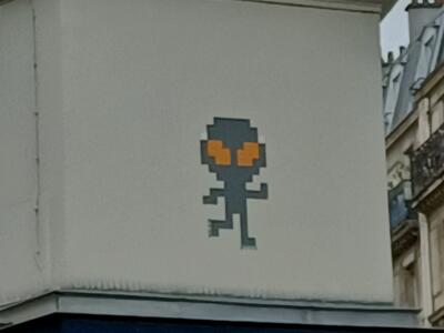 Alien pixelisé aux yeux orange — Street art de Mr Djoul à Paris