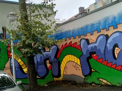 Green dragon and purple letters — Street art in Köln