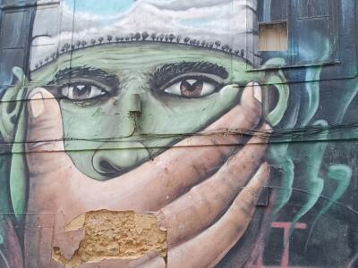 Silenced Green Face and Caravel — Street art in Almada