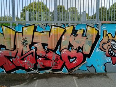 Yellow lettering at the skatepark — Street art in Yffiniac
