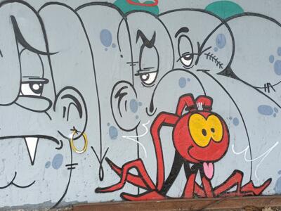 Lettrage gris et créature rouge — Street art à Plérin
