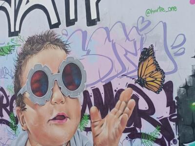 Child with Round Glasses and Butterfly by Harte One — Street art by Harte One in Almada