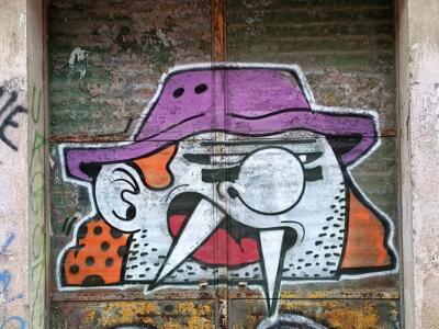 Oiseau au chapeau violet sur porte de tôle — Street art à Almada