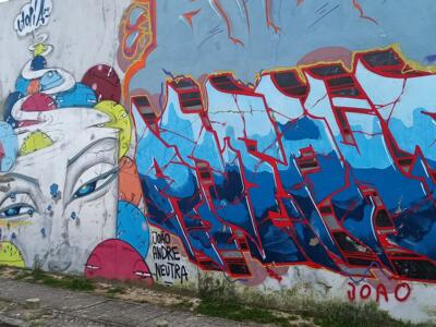 Lettrage bleu et rouge et visage aux chapeaux — Street art de Utopia à Almada