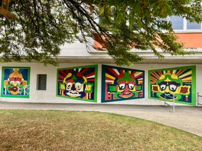 Four masks on sunburst backgrounds — Street art in La Chaux-de-Fonds