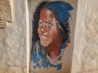 Enfant rieur au foulard bleu dans une niche — Street art à Erriadh