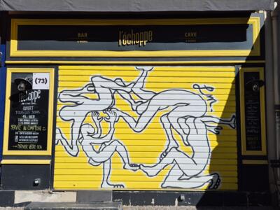 Corps entremêlés sur le rideau de l'échoppe — Street art à Arles