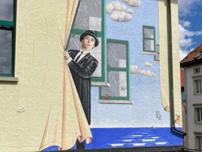The Man at the Curtain — Street art by Carolus in La Chaux-de-Fonds