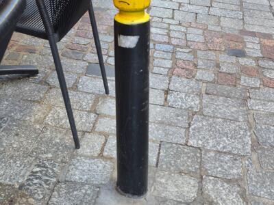 Tête de Lego renfrognée sur un potelet — Street art de Le CyKlop à Clermont-Ferrand
