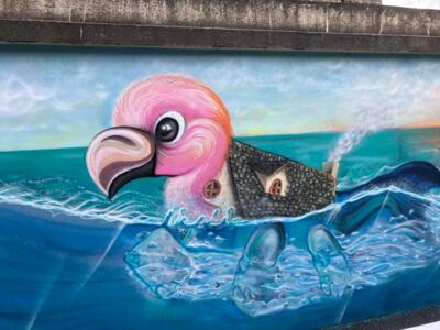 Oiseau rose portant une maison de pierre — Street art de Mista Drop à Cancale